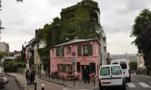 Urokliwa ulica na Montmartre z różową kawiarnią La Maison Rose i budynkiem obrośniętym bluszczem.