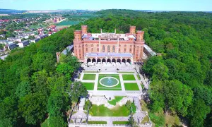 Kamieniec Ząbkowicki zamek, otoczony bujną zielenią, prezentuje swoją neogotycką architekturę z wieżami i arkadowym dziedzińcem.
