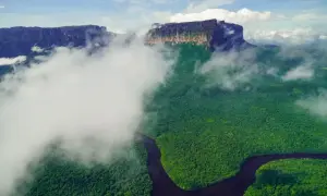 Mgliste chmury otulają zielony las i krętą rzekę, odsłaniając majestatyczne góry. Widok jak z **Angel Falls**.