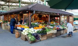 Kolorowy stragan na Kleparzu pełen świeżych warzyw i owoców. Klienci wybierają produkty, tworząc tętniącą życiem scenę.