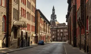 Charakterystyczna zabudowa Nikiszowca z ceglanymi kamienicami i wieżą kościelną w tle.