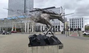 Metalowy jednorożec na skalnej podstawie, symbolizujący dynamikę i nowoczesność, na tle architektury Piotrkowska Łódź.