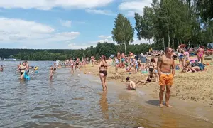 Tłumy ludzi korzystają z kąpieliska, plaży i wodnych atrakcji w słoneczny dzień.