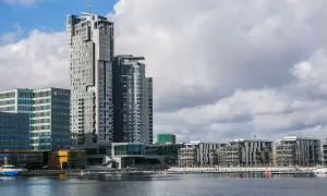 Nowoczesne sea towers w Gdyni, zdominowane przez szare i białe fasady, odbijają się w spokojnej wodzie portu.