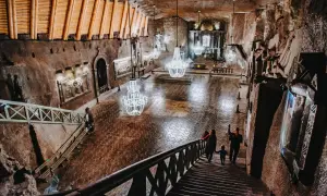 Wielka komora w kopalni soli Wieliczka, z kryształowymi żyrandolami i turystami schodzącymi po schodach. Sprawdź kopalnia soli Wieliczka cennik.