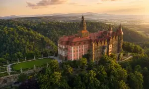 Zamek Książ, jedna z największych atrakcji Dolnego Śląska, w otoczeniu zielonych wzgórz o zachodzie słońca.