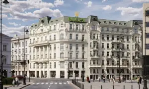 Elegancki budynek z logo Rolex na dachu, symbolizujący nowy świat w Warszawie. Ulica tętni życiem, ludzie spacerują, a samochody przejeżdżają.