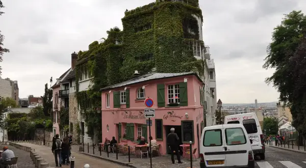Urokliwa ulica na Montmartre z różową kawiarnią La Maison Rose i budynkiem obrośniętym bluszczem.