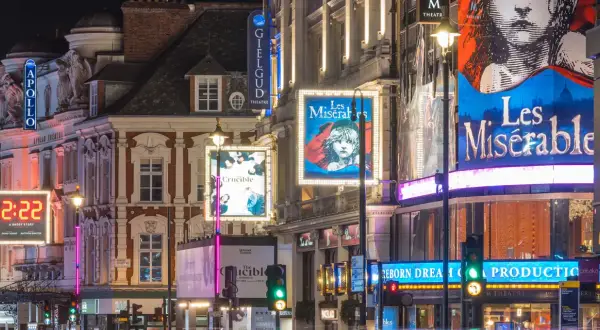 Tętniący życiem west end nocą, z neonami teatrów Apollo, Gielgud i plakatami "Les Misérables" oraz "The Crucible".