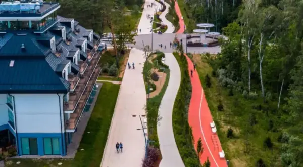 Nowoczesny deptak w Świnoujściu z hotelami i ścieżkami rowerowymi w otoczeniu zieleni.
