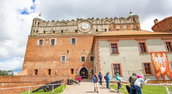 Zamek Golubski, jedna z głównych atrakcji Golubia-Dobrzynia, z turystami zwiedzającymi dziedziniec.