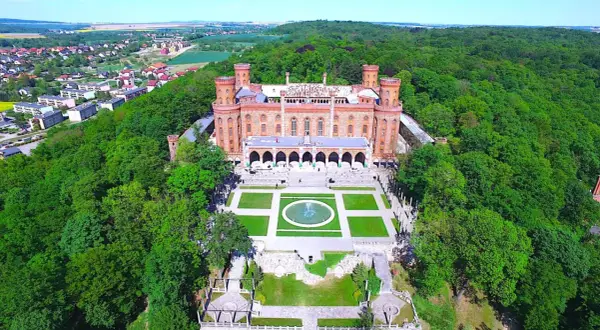 Kamieniec Ząbkowicki zamek, otoczony bujną zielenią, prezentuje swoją neogotycką architekturę z wieżami i arkadowym dziedzińcem.