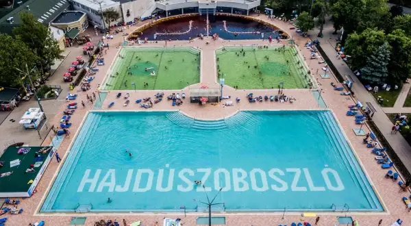 Hajdúszoboszló baseny cennik: aerial view of a large complex with multiple pools, including a vast blue pool with "HAJDÚSZOBOSZLÓ" written on the bottom.