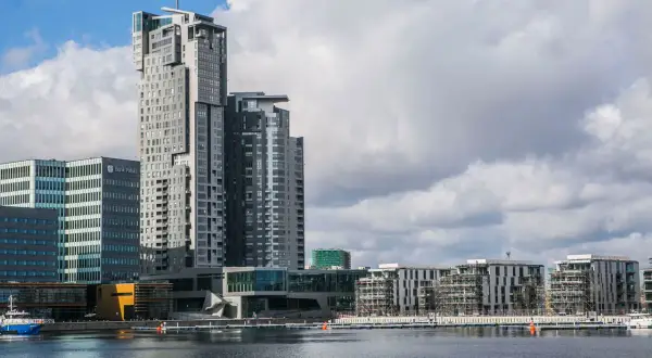 Nowoczesne sea towers w Gdyni, zdominowane przez szare i białe fasady, odbijają się w spokojnej wodzie portu.
