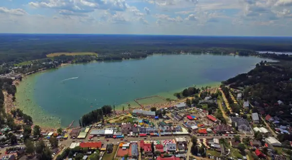 Okuninka: mnóstwo ludzi na plaży i w wodzie, karuzele i inne atrakcje dla dzieci.
