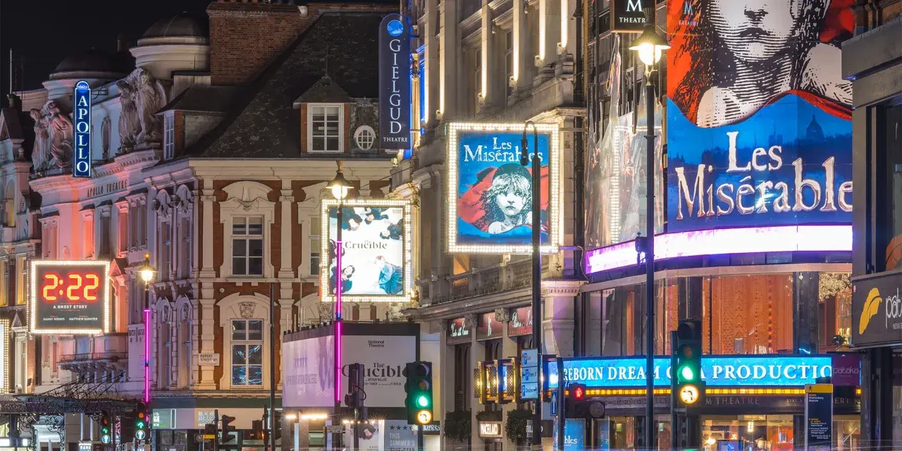 Tętniący życiem west end nocą, z neonami teatrów Apollo, Gielgud i plakatami "Les Misérables" oraz "The Crucible".