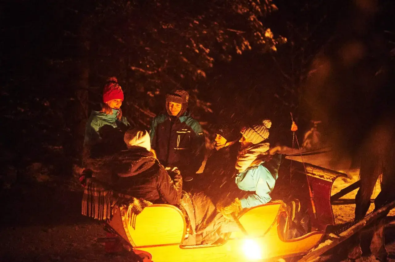 Zakopane kulig z ogniskiem: grupa przyjaciół w saniach, rozgrzewa się przy ognisku. Cena tej zimowej atrakcji jest przystępna.