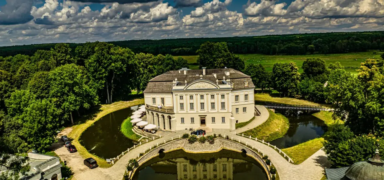 Pałac w Kurozwękach, otoczony fosą i parkiem, to wspaniałe atrakcje. Widać mostki, stawy i otaczający las.