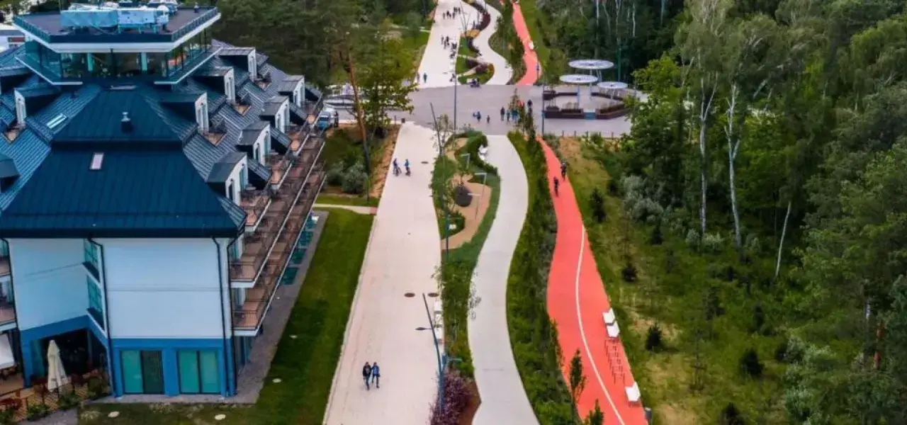 Nowoczesny deptak w Świnoujściu z hotelami i ścieżkami rowerowymi w otoczeniu zieleni.