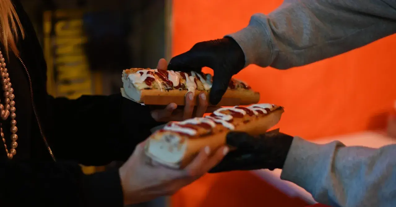 Pyszne hot-dogi z sosem i posypką na nocnym targu w Warszawie.