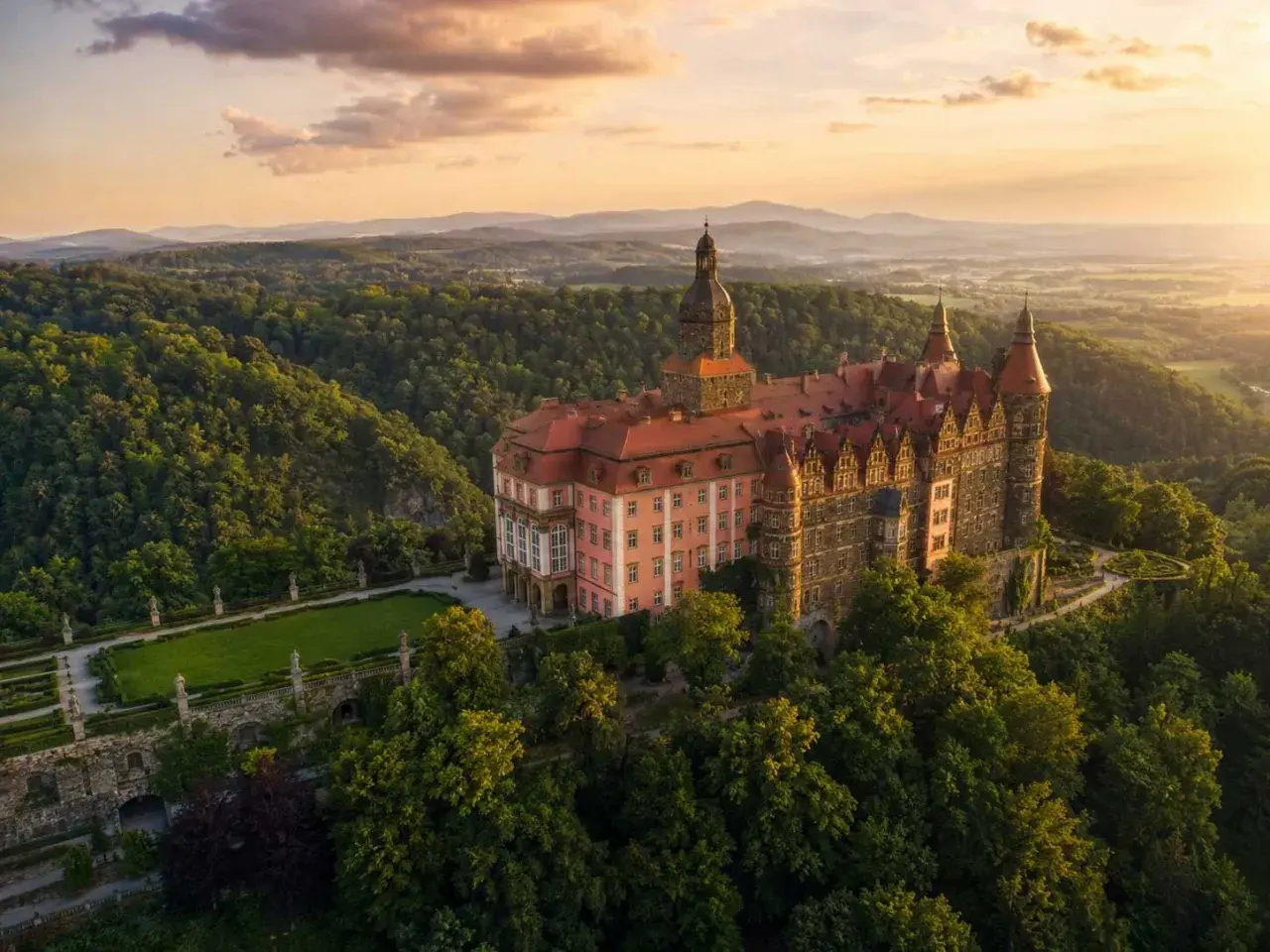 Zamek Książ, jedna z największych atrakcji Dolnego Śląska, w otoczeniu zielonych wzgórz o zachodzie słońca.
