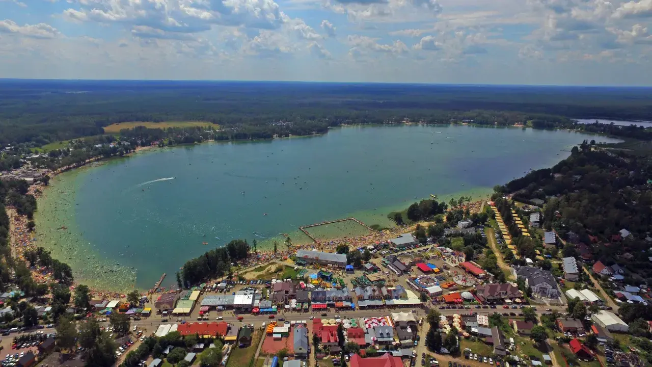 Okuninka: mnóstwo ludzi na plaży i w wodzie, karuzele i inne atrakcje dla dzieci.