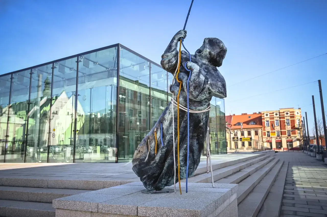 Rzeźba w częstochowa stare miasto, na tle nowoczesnego budynku i kamienic.