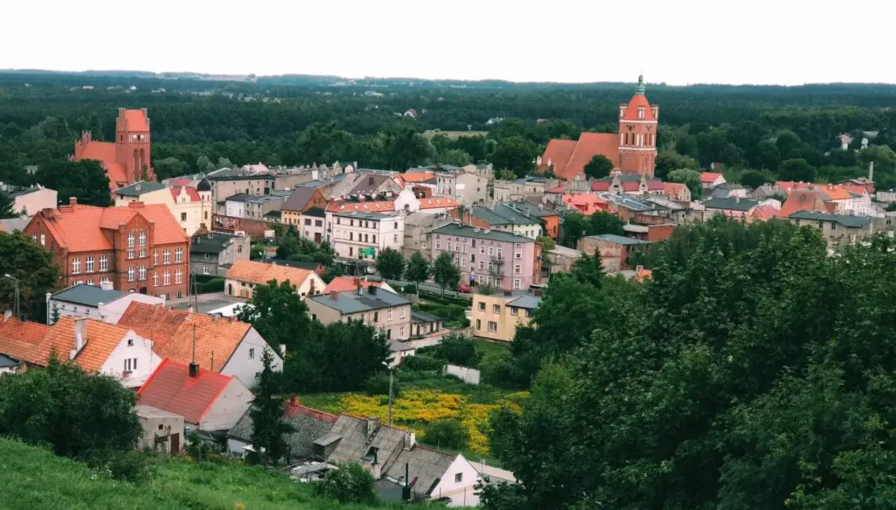 Widok na miasto Golub-Dobrzyń z charakterystycznymi czerwonymi dachami i wieżami kościołów. Atrakcje turystyczne miasta są widoczne z daleka.