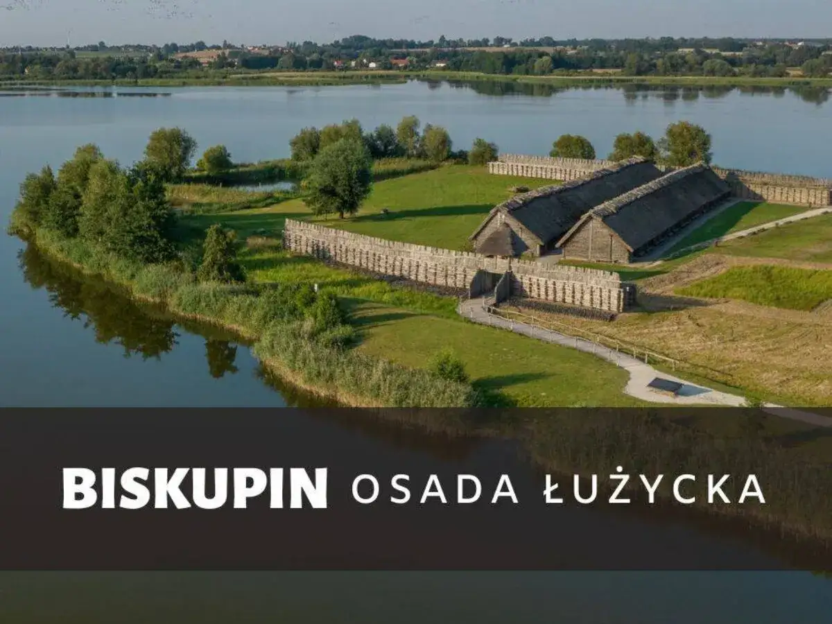Biskupin atrakcje: zrekonstruowana osada obronna nad jeziorem, z drewnianymi domami i wałami.