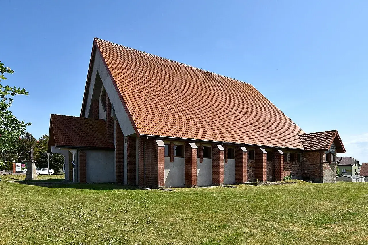 Nowoczesny kościół w Jarosławcu z czerwoną, ceramiczną dachówką i ceglanymi elementami architektonicznymi.