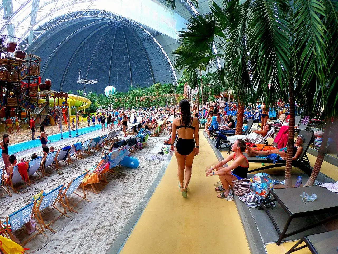 Tropical island cennik: plaża, palmy, zjeżdżalnie i ludzie relaksujący się pod ogromną kopułą.