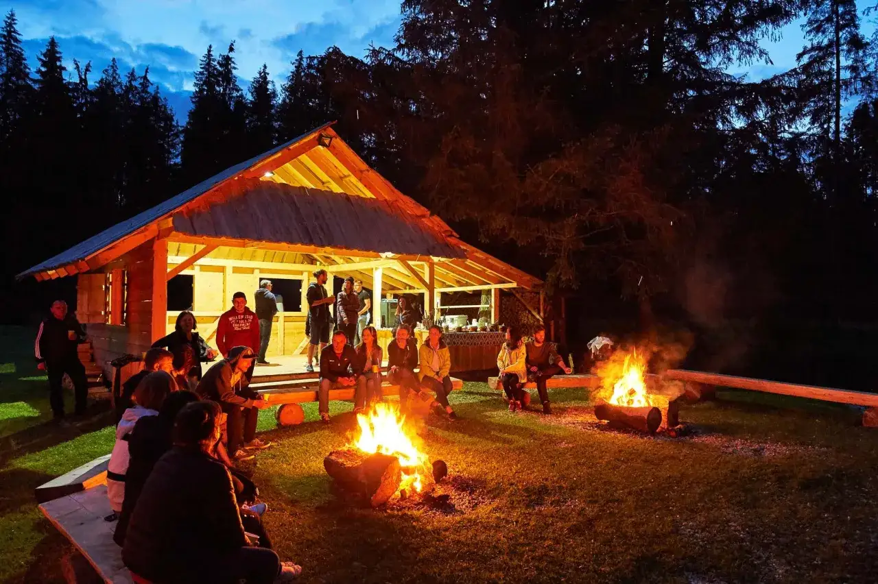 Grupa ludzi przy ognisku w góralskiej chacie. Idealne miejsce na kulig z ogniskiem w Zakopanem. Cena do ustalenia.