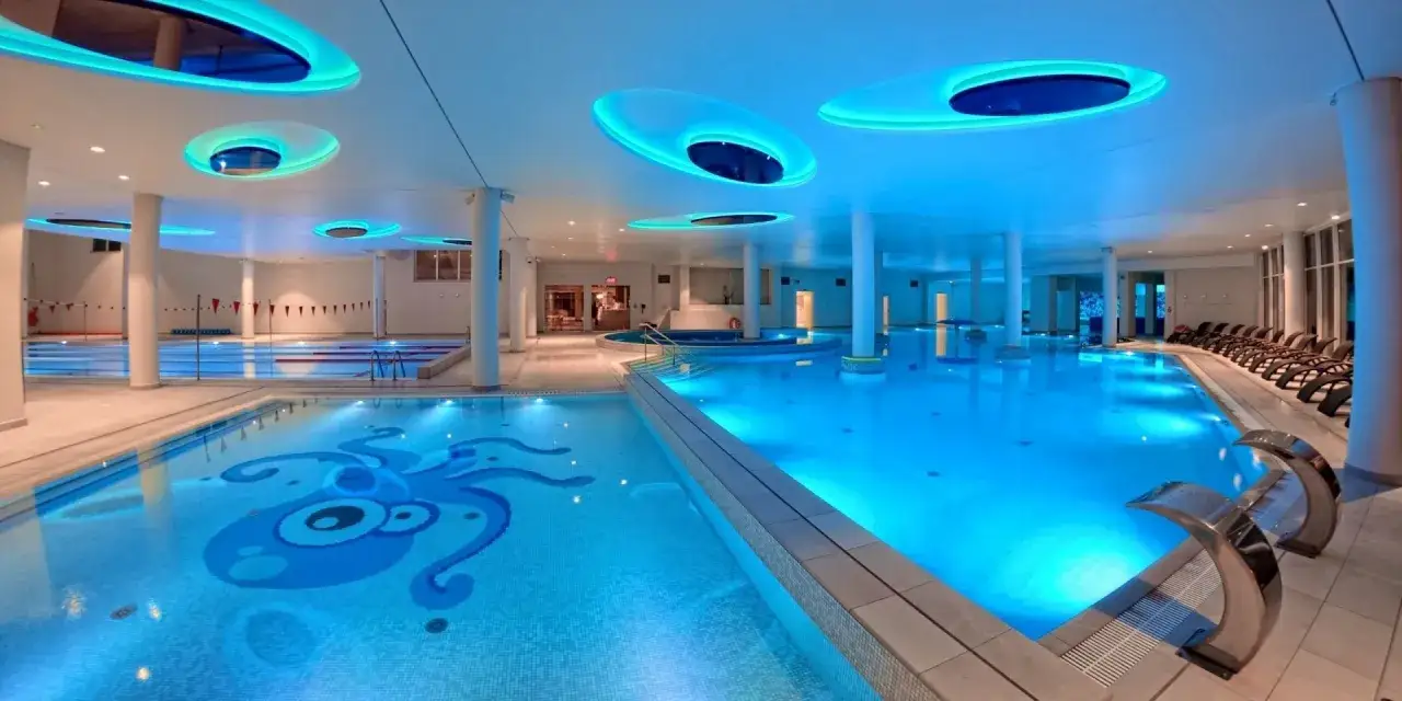 Nowoczesny aquapark Ustka z basenami, jacuzzi i niebieskim podświetleniem. Na dnie basenu dla dzieci widoczny jest niebieski stwór.