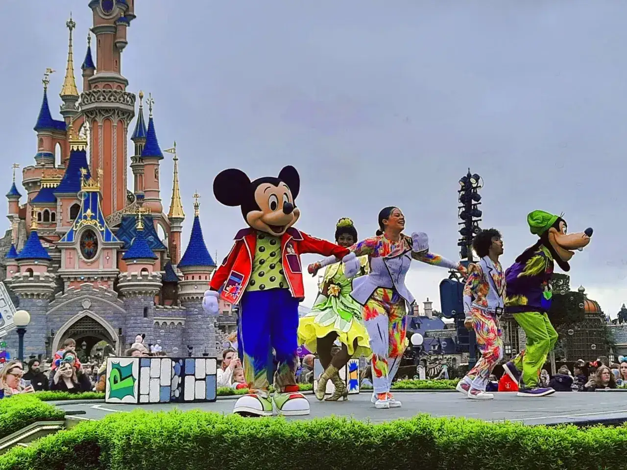 Myszka Miki i przyjaciele tańczą na scenie przed zamkiem w Disneylandzie.