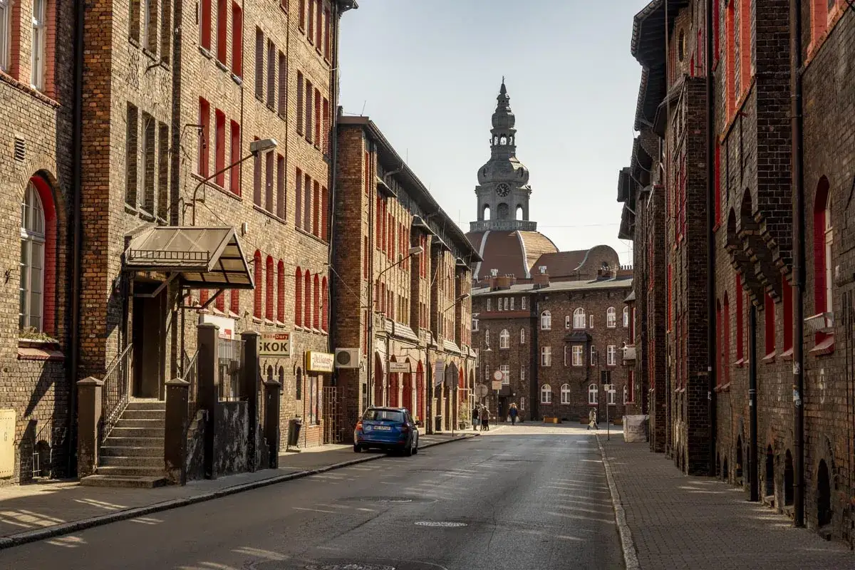 Charakterystyczna zabudowa Nikiszowca z ceglanymi kamienicami i wieżą kościelną w tle.